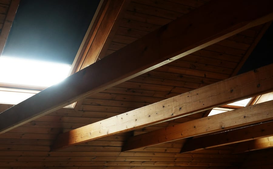 Roof rafters and boarding seen from inside an attic, lit from one side